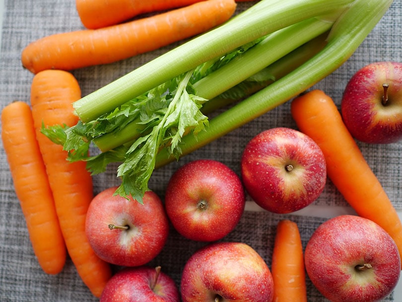 एक मेज पर अजवाइन, सेब और गाजर