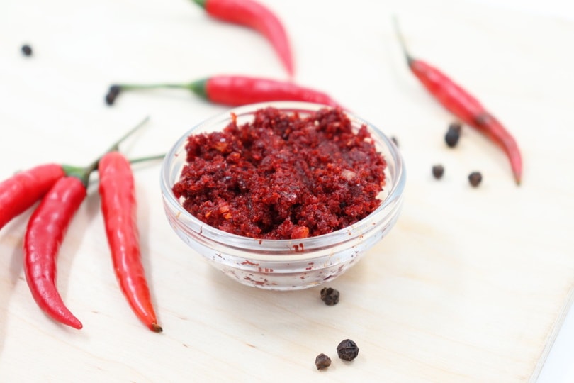 Minced chili in a small bowl with peppercorns nearby