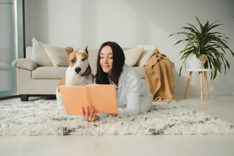 woman reading book with her dog