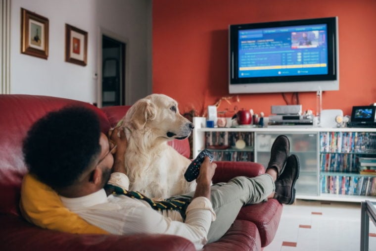 man watching TV with his dog