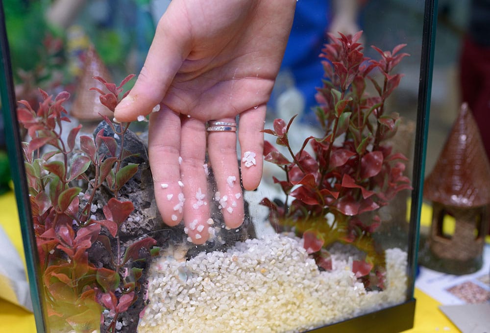 person adding substrate and sand in the tank