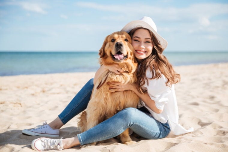 woman hugging her dog on the beach