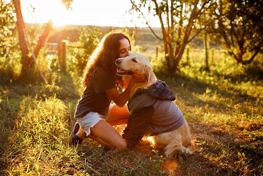 Woman in brown hugging a golden retriever_Helena Lopes_Unsplash