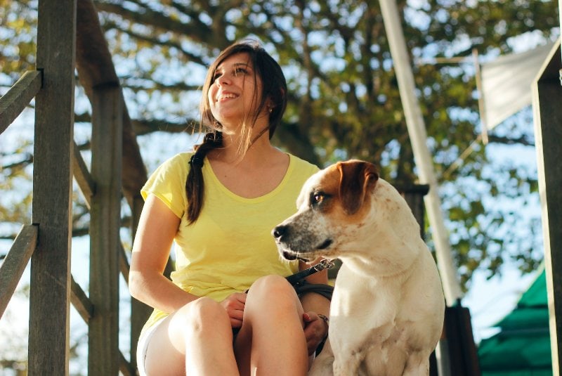 woman in yellow shirt sitting on stairs with a dog