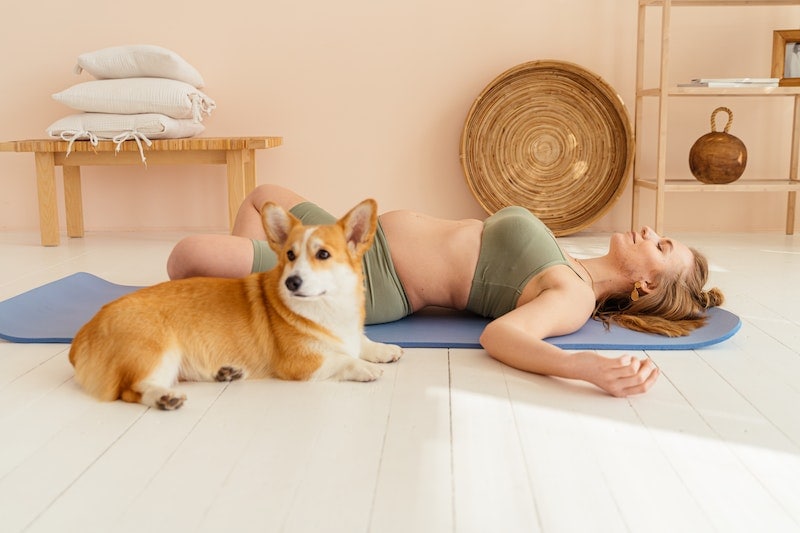 Woman doing yoga beside a dog