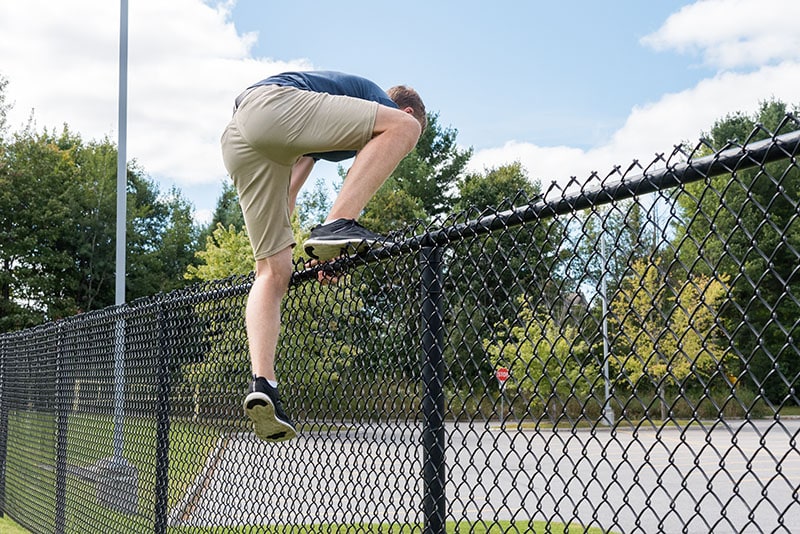 man climbing a metal fence