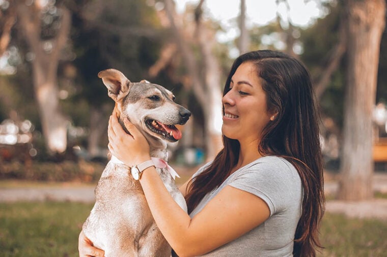 smiling dog beside a smiling woman