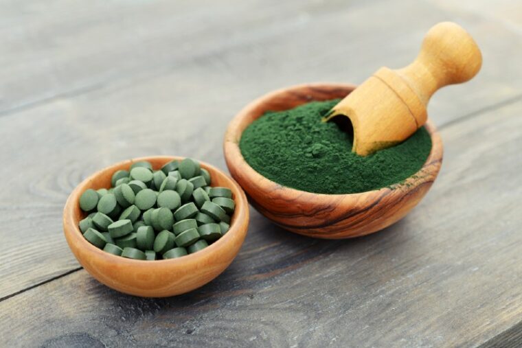 spirulina powder and tablets in a wooden bowl