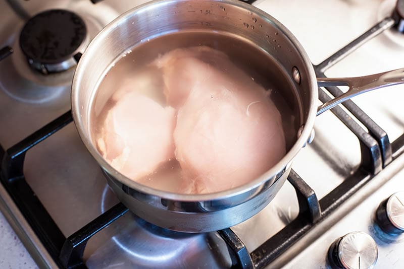 Boiling chicken breast in a saucepan on a gas stove
