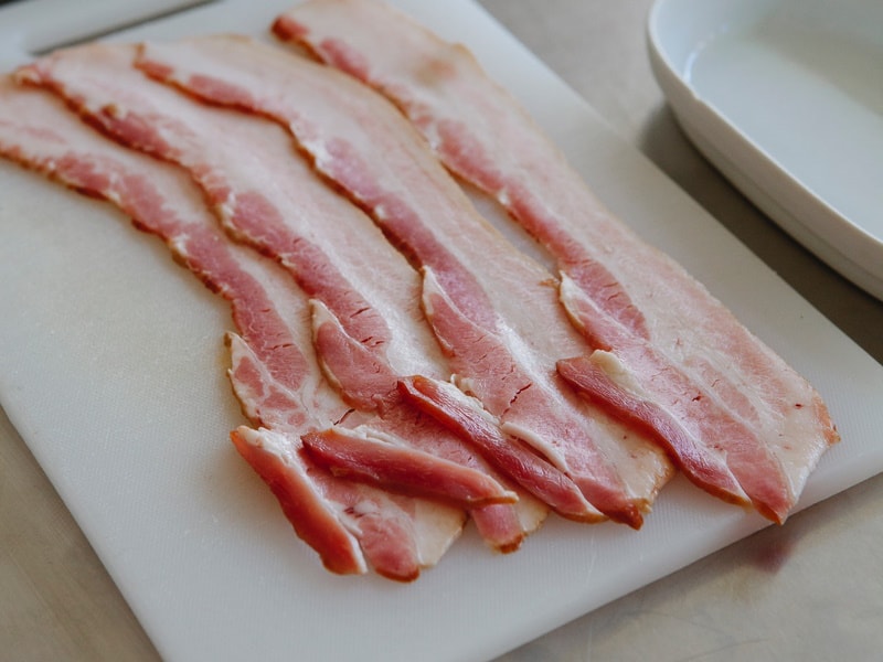 Slices of raw bacon on cutting board