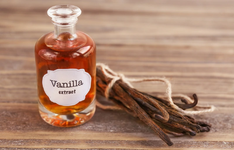 bottle of vanilla extract beside vanilla beans