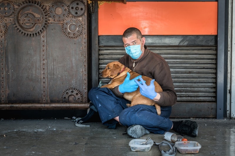 Un hombre sin hogar con un perro en su regazo
