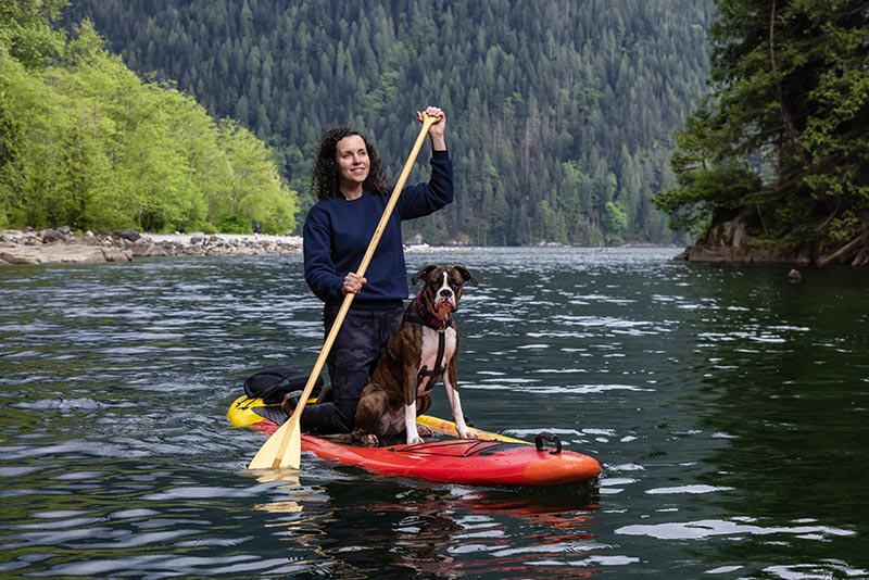 woman on a paddle board with boxer dog
