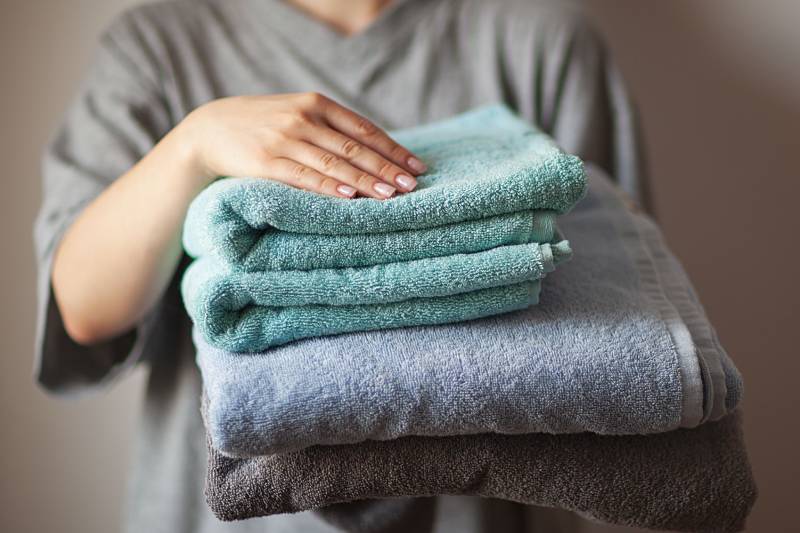 female hand holding stack of clean bath towels