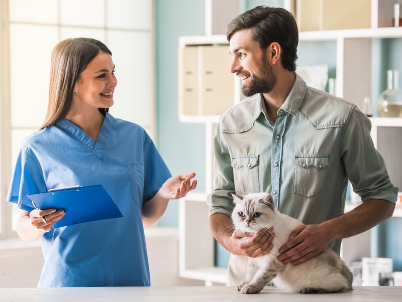 man holding cat in vet clinic