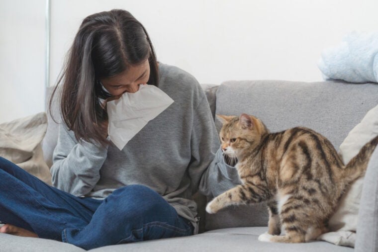 woman sneezing near her cat