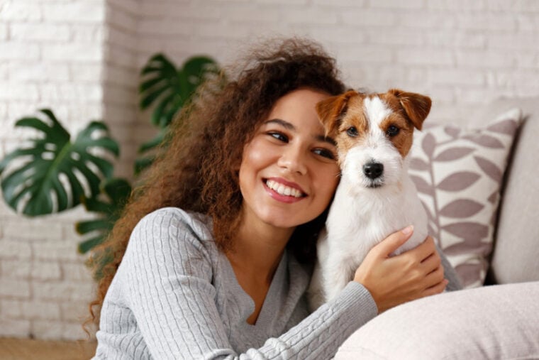 young woman hugging her jack russel terrier puppy at home