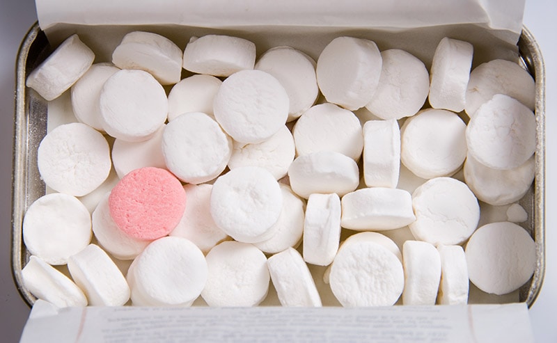 one pink mint candy surrounded with white mint candies