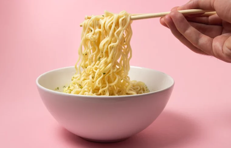 cooked instant noodles in a bowl being picked up with chopsticks